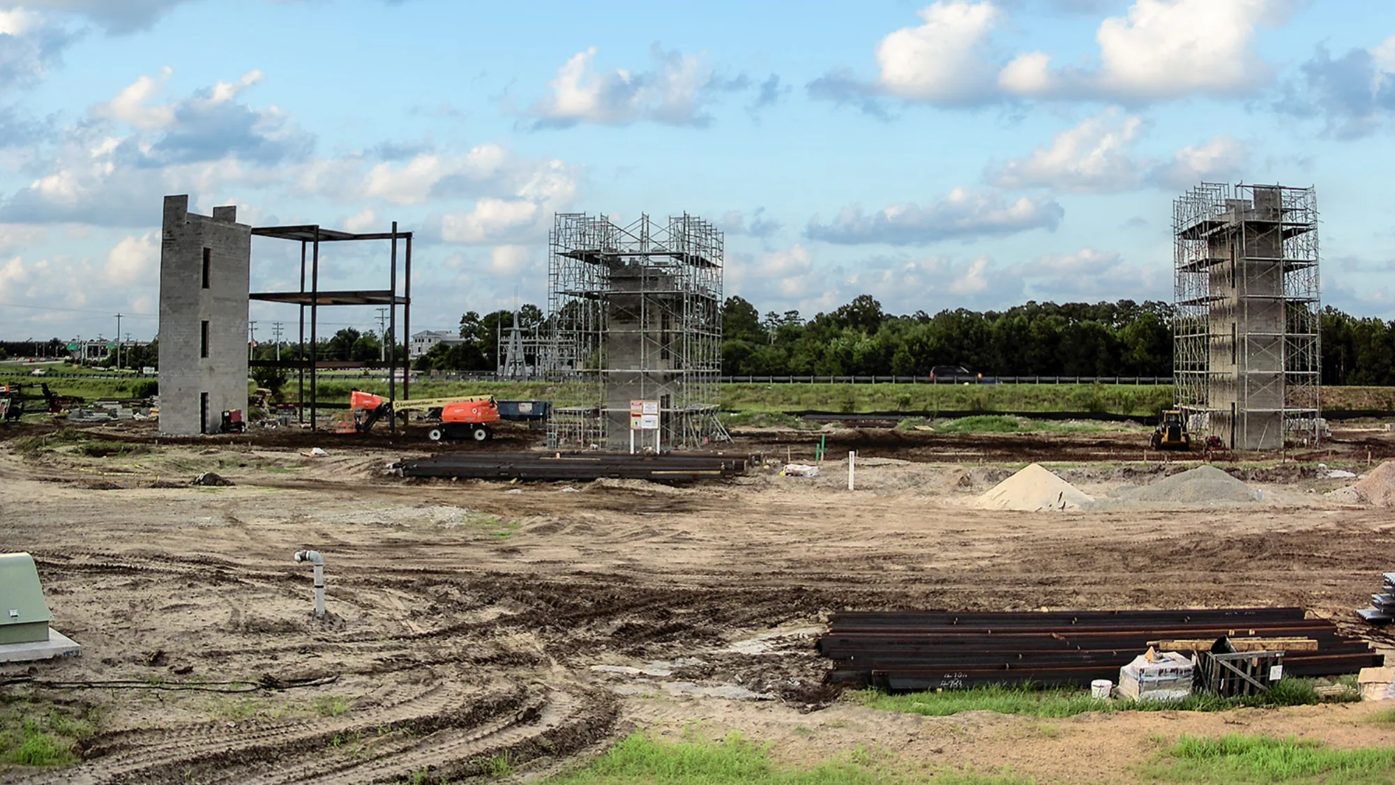 Construction progress at The CURRENT Building — concrete cores rising with scaffolding and steel framing underway
