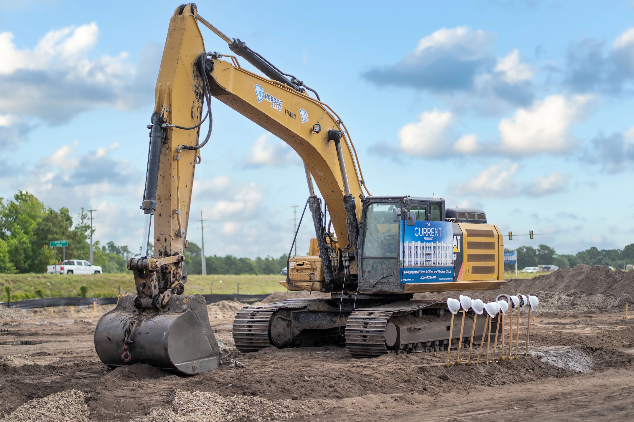 Excavator with The CURRENT Building banner and ceremonial shovels at the groundbreaking